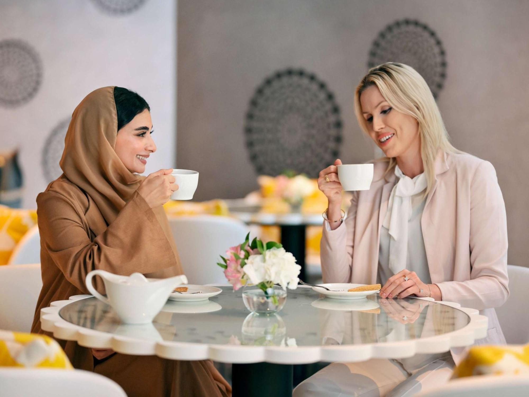 Moevenpick Hotel & Apartments Ghala Mascate Extérieur photo Two women drinking coffee
